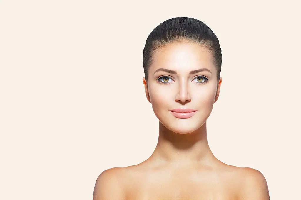 Frau mit hochgestecktem dunklem Haar und nackten Schultern vor hellem Hintergrund.